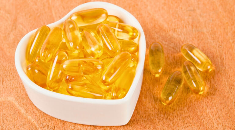 Close-up of fish oil capsules with healthy heart icon, emphasizing cardiovascular health.